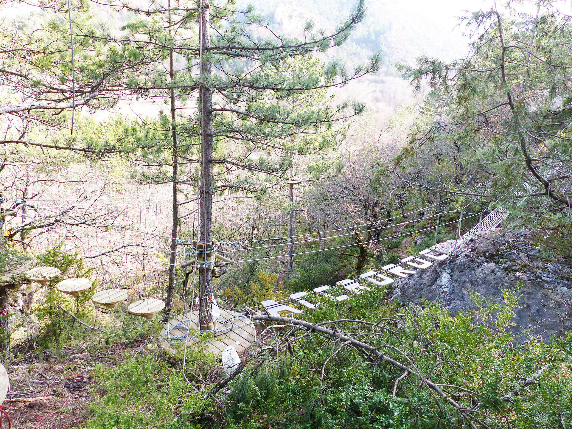 Passerelle entre arbres et rochers à Accroroc